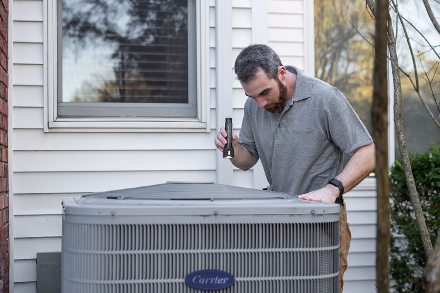 Technician inspecting an outdoor HVAC unit for maintenance