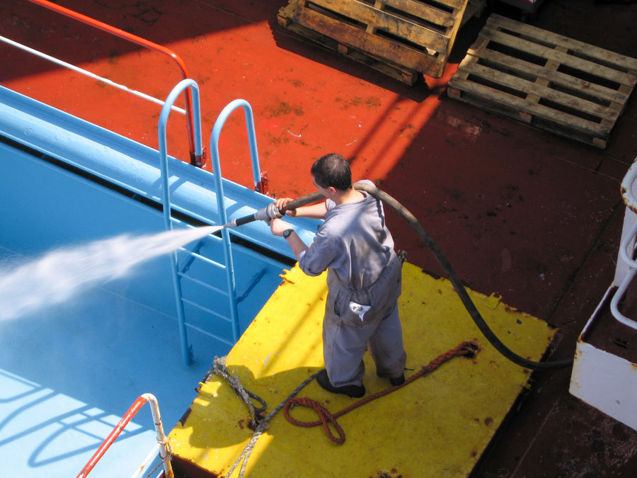 Worker cleaning an industrial surface with a high-pressure hose