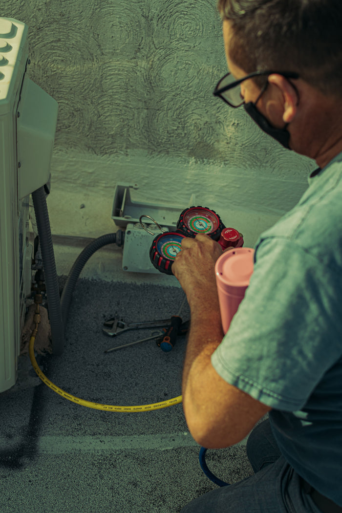 Technician checking and repairing an HVAC system with tools and gauges